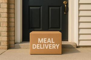 Meal delivery box left at front door of suburban house during daytime, contactless food service concept photo