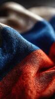 Fabric close-up shows detailed texture and vibrant colors of a flag in rich hues of blue, white, and red under soft lighting photo
