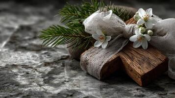 Decorative wooden cross with flowers and greenery on textured stone surface photo