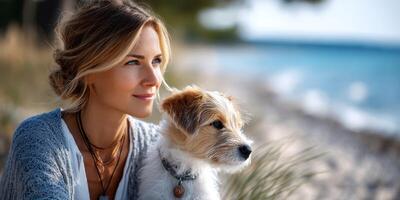 Woman enjoying a serene moment at the beach with her dog during a sunny afternoon by the water photo