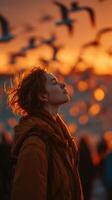 Young woman enjoying a sunset with birds flying in the background at a beach during evening hours photo