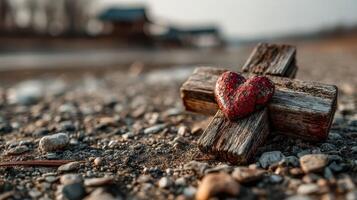 Heart-shaped stone rests on a rustic wooden cross by a riverbank during golden hour showcasing natural beauty and tranquility photo