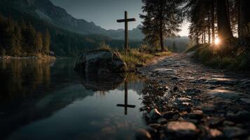 Morning light illuminates a cross by the lakeside with mountains in the background photo