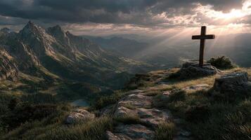 Mountain landscape at sunset highlighting a wooden cross atop a rocky hill under moody clouds photo