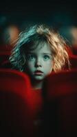Child with curly hair watching a movie in a dark theater, captivated by the screen lights and colors photo