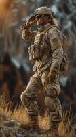 Soldier saluting at sunset atop a mountain overlooking a vast valley during a military training exercise photo