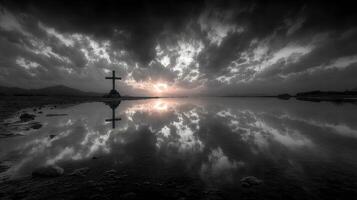 Cloudy sunset reflected in still water with a cross in the foreground on an overcast evening photo