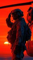 Soldier salutes against a striking sunset backdrop while helicopter prepares for departure photo