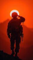 Soldier saluting against sunset backdrop in mountainous terrain during evening hours photo