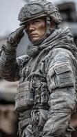 Soldier in military gear saluting with a serious expression in a dusty terrain during training operations photo