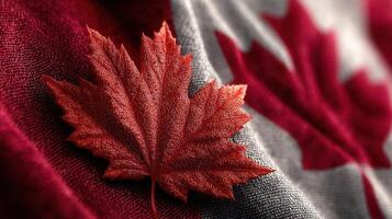 Close-up of a red maple leaf on a textured Canadian flag during autumn season celebrating national identity photo