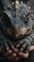 Close-up of a unique reptilian creature being held gently outdoors in a natural setting during daylight photo