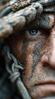 Intense gaze of a warrior covered in mud and paint during a survival exercise in the wilderness photo