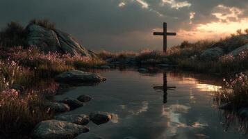 Cross reflected in calm water under a cloudy sky at sunset near rocky terrain photo