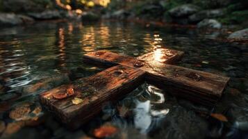 Water reflects sunlight on a wooden cross resting among rocks in a serene stream surrounded by autumn leaves photo
