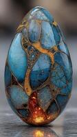 Unique blue and gold decorative egg with intricate patterns displayed on a reflective surface photo