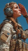 Soldier in military gear saluting against a clear blue sky during training exercise in rugged terrain photo