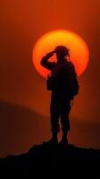 Soldier salutes at sunset with a vibrant orange sun in the background highlighting bravery and dedication photo