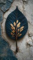 Unique artistic representation of a dried leaf with golden details against a cracked wall background photo