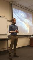 Educator presents on meteorological phenomena in a classroom setting with storm imagery projected photo