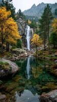 Majestic waterfall cascading into a tranquil pool surrounded by vibrant autumn foliage in a mountain landscape photo