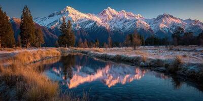 Snow-capped mountains reflect in tranquil waters during early morning light near a serene stream in New Zealand photo