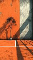 Orange wall provides striking backdrop for a solitary tree casting shadows on a court during late afternoon photo