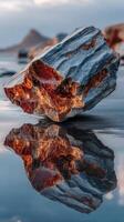 Beautiful rocky landscape featuring a unique stone formation reflecting on calm water at sunset photo