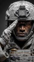 Soldier saluting in winter gear with frost covering helmet and uniform in a dramatic portrait photo