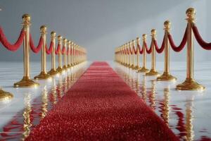 Red carpet lined with golden stanchions welcomes guests at an elegant event venue on a sunny day photo