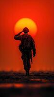 Soldier saluting at sunset with vibrant orange sky and silhouette against the horizon in a serene moment photo