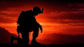 Soldier kneeling in silhouette during sunset in a mountainous terrain reflecting dedication and quiet reflection photo