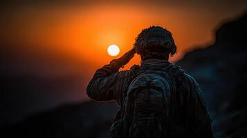 Soldier salutes at sunset in mountainous terrain during military operations photo