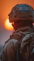Soldier observing sunset with flag on helmet in desert during military operation photo