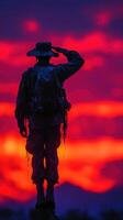 Soldier saluting at sunset with vibrant colors illuminating the sky in the background photo