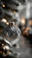Elegant glass ornament hanging on a Christmas tree branch with soft bokeh lights in the background photo
