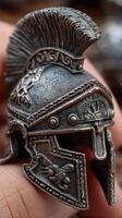 Detailed miniature Roman gladiator helmet held in hand with intricate metalwork at a display event during afternoon light photo