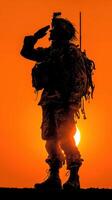Soldier salutes at sunset in a remote location, showcasing dedication and bravery with a backdrop of vibrant orange skies photo