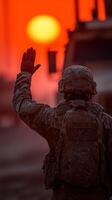 Soldier waves goodbye against a striking sunset in a military area photo