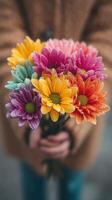 Colorful bouquet of daisies held by a person in a cozy outfit on a chilly day photo