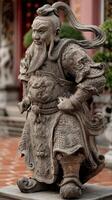 Stone warrior statue stands proudly in a temple courtyard surrounded by lush greenery and ornate architecture photo