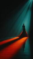 Elegant model in captivating black gown illuminated by dramatic spotlight during fashion show at night photo