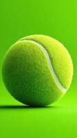 Bright green tennis ball resting on vivid green surface, showcasing texture and color contrast with focus on sports equipment photo