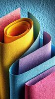 Colorful rolled sheets of textured paper creating an artistic arrangement on a vibrant background photo