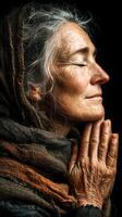 Elderly woman in quiet reflection with hands clasped, warm lighting and natural textures emphasize her wisdom and serenity photo