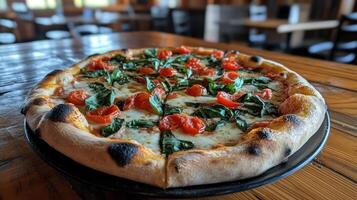 A pizza on a black plate with tomatoes and spinach photo