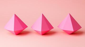 Three pink paper triangles on a pink background photo