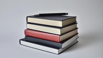 A stack of books with a pen on top photo