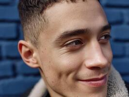 Close-up portrait of a young person with short hair, looking to the side with a slight smile. The focus is on the facial expression, capturing a moment of contemplation photo