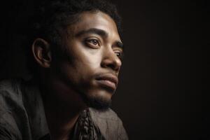 Thoughtful man gazing into distance, highlighting facial expressions and emotions, wearing a patterned shirt. Soft lighting accentuates features, creating a contemplative mood photo
